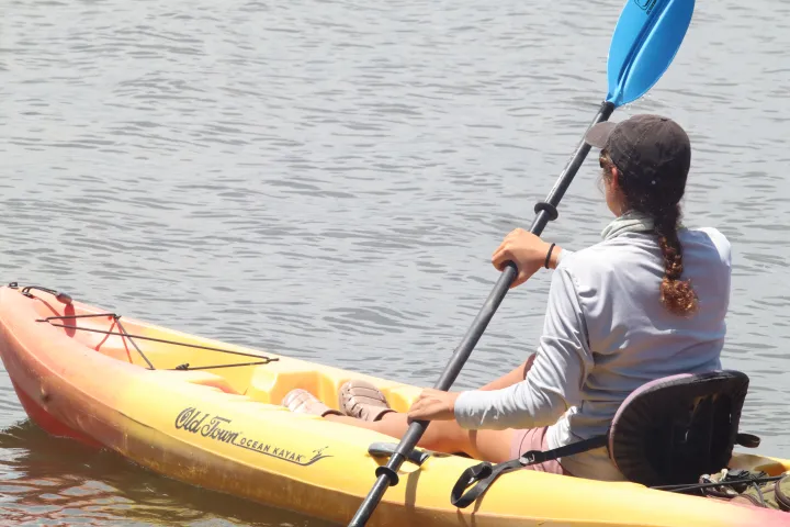 Person in a yellow kayak paddles on calm water.