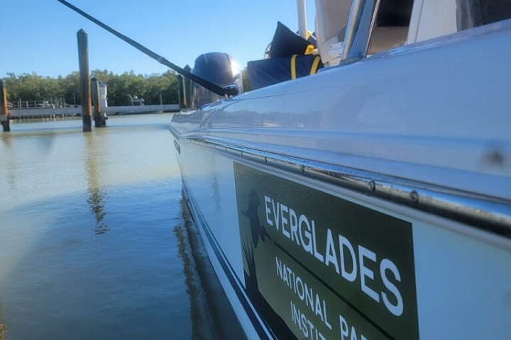 Close-up of a boat with 'Everglades National Park Institute' sign near a calm water area.