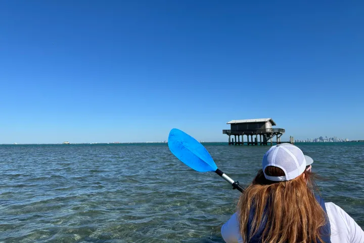 a man holding a kite while standing in a body of water
