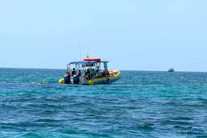 People on a yellow boat in the ocean under a clear blue sky.